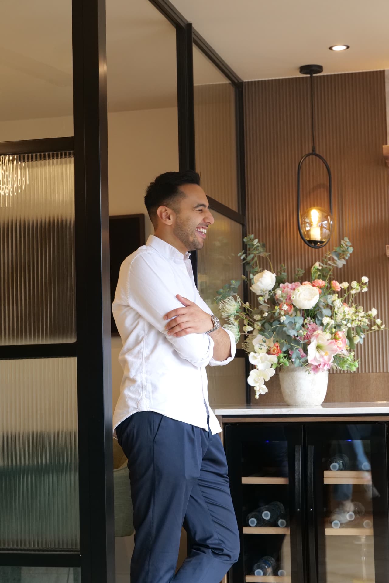 A member of the Cobham Dental team standing in the waiting area beside a fluted glass screen and a vase of flowers